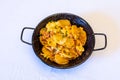 Top closeup Spanish Paella in a black pan on the white background