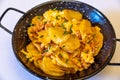 Top closeup Spanish Paella in a black pan on the white background