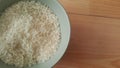 Top closeup view of heap of rice in a ceramic bowl placed over wooden floor