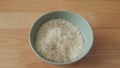 Top closeup view of heap of rice in a ceramic bowl placed over wooden floor Royalty Free Stock Photo