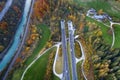 Top dawn aerial view of freeway speed road going out from undeground tunnel between yellow autumn forest trees and blue river Royalty Free Stock Photo