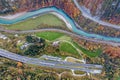 Top dawn aerial view of freeway speed road going out from undeground tunnel between yellow autumn forest trees and blue river Royalty Free Stock Photo