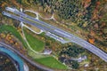 Top dawn aerial view of freeway speed road between yellow autumn forest trees and blue river Royalty Free Stock Photo