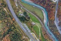 Top dawn aerial view of freeway speed road between yellow autumn forest trees and blue river Royalty Free Stock Photo