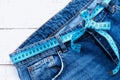 Top of denim trousers, on a wooden background. jeans with a measuring tape