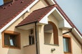 Top detail front of big modern expensive residential family cottage with shingled brown roof, brick chimney, stucco walls on blue