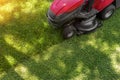 Top down above view of professional lawn mower worker cutting fresh green grass with landcaping tractor equipment