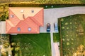 Top down aerial view of a private house with red tiled roof and spacious yard with parked two new cars