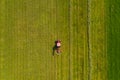 Top down aerial view of a red tractor cultivating farmland with a spinning rack