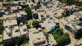 Top down aerial view of small houses in suuny wearther with grassy fields and roads , traffic. Camera is raising up over bulidings