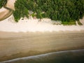 Top down aerial view of sun umbrellas on a large, quiet tropical beach at low tide