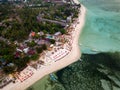 Top down aerial view of tables and seats on a tropical sandy beach during sunset on a small island