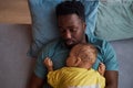 Top down Black father with baby son sleeping together at naptime