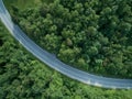 TOP DOWN: Cool shot of long curve of asphalt road running through the forest. Royalty Free Stock Photo