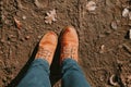 Top down dirty yellow laced boots in the mud, woman in blue jeans Royalty Free Stock Photo