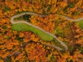 TOP DOWN: Drone view of a road winding through the woods changing colors in fall Royalty Free Stock Photo