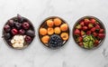 A top down horizontal row of three trays of tasty fruit. A complimentary colours concept.