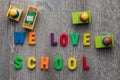 Top down shot of the sentence "We love school" written in single letter on the ground.