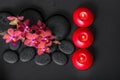 top down spa setting of blooming twig red orchid flower, phalaenopsis with water dew and candles on zen basalt stones, closeup