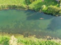 TOP DOWN: Tourists lie across a canoe as friend paddles them along a lazy river Royalty Free Stock Photo