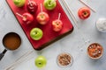 Top down view of apples on a pan surrounded by ingredients to make caramel apples for Halloween. Royalty Free Stock Photo