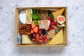 Top down view of assortment of fruits cheeses crackers in a box isolated on marble pattern table background. Concept for food