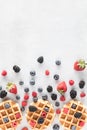 Top down view of Belgian waffles with berries in an abstract arrangement.