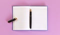 Top down view - black fountain ink pen with gold nib, opened cap, empty white paper pad on lilac board under Royalty Free Stock Photo