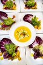 Top down view of Bowl of butternut squash soup on top of cabbage,kale and tomato salads ready for a catered dinner