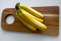 Top down view of a bunch of yellow bananas which are laying on a wooden cutting board Royalty Free Stock Photo