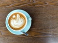 A top-down view of a caffeinated latte featuring intricate swan latte art in a light blue ceramic cup. Royalty Free Stock Photo