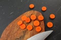 Top down view, carrot sliced to circles, chopping desk, blade of chef knife next on black marble like working board