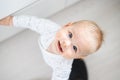 top down view of cheerful baby boy infant taking first steps holding to kitchen drawer at home. Cute baby boy learning Royalty Free Stock Photo