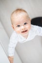 top down view of cheerful baby boy infant taking first steps holding to kitchen drawer at home. Cute baby boy learning Royalty Free Stock Photo