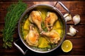 top-down view of chicken legs in a saucepan, bubbling with hot garlic butter