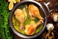 top-down view of chicken legs in a saucepan, bubbling with hot garlic butter