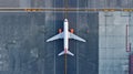 Top down view on commercial airplane docking in terminal in the parking lot of the airport apron, waiting for services Royalty Free Stock Photo