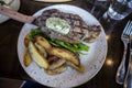 Top down view of a delectable steak frites dinner on a wooden table inside a restaurant