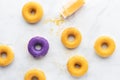 Top down view of donuts on a white marble background with a bottle of yellow sprinkles tipped over and spilling out. Royalty Free Stock Photo