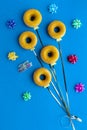 Top down view of donuts with yellow icing on blue paper on strings to resemble a bunch of balloons. A birthday concept. Royalty Free Stock Photo