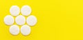 Top down view, 7 face cleaning cotton pads arranged in circle, on yellow board, wide banner space for text right