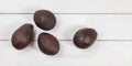 Top down view, four ripe brown avocados on white boards desk Royalty Free Stock Photo