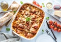 A top down view of a freshly baked lasagna cut into slices ready for serving and surrounded by Italian ingredients. Royalty Free Stock Photo