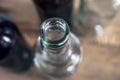 Top-Down View of Glass Bottle Rim, Bore, Orifice or Throat. Blurred Empty Glass Bottles, Wooden Background. Healthy Living and