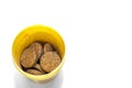 Top-Down View of Herbal Supplement Pills in a Yellow Plastic Container on White Background