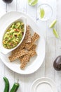 Top down view of homemade guacamole served with rustic multigrain crackers.