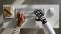 Top-down view of a human hand and a robotic hand typing together on a keyboard Royalty Free Stock Photo