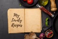 Top-down view of a kitchen table with ingredients, utensils, and an open cookbook