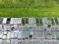Top down view of a large, abandoned green house showing multiple broken glass roof structures.