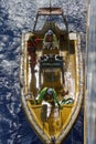 Top down view of launching or recovering yellow Fast Rescue Boat (FRC) from ship. Three crew members onboard.